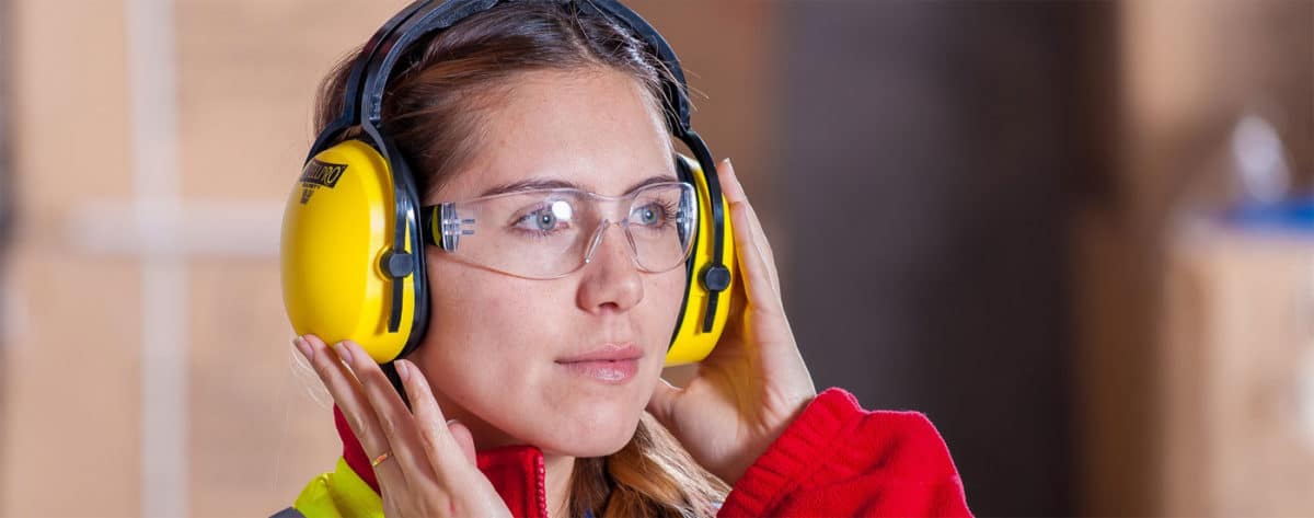 Eine Alleinarbeiterin mit Schutzbrille und Gehörschutz als ein Beispiel für Alleinarbeiterschutz